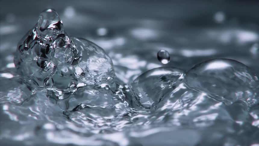 Bubbles are rising up over the surface of water and splashing in the light