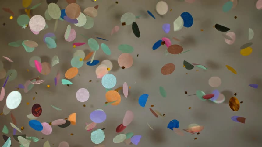Circles of colorful paper confetti and glitter falling and floating down