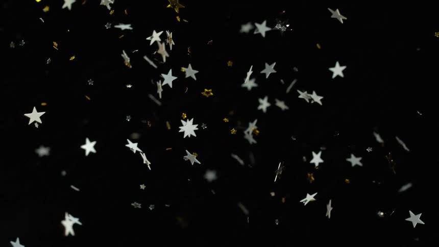 Silver and gold stars twist and shine as they fall in the darkness
