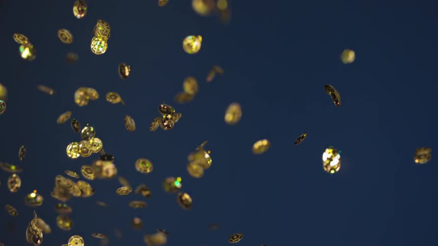A handful of gold sequins is moving through the air in slow motion