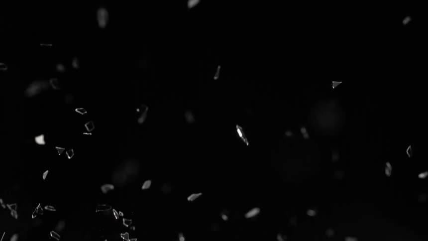 Shards of glass fly into the air against a darkbackground then fall again