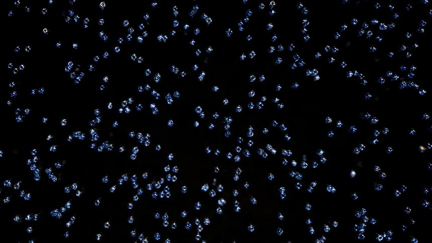 Rough cut diamonds and micro beads move in reverse on the black background