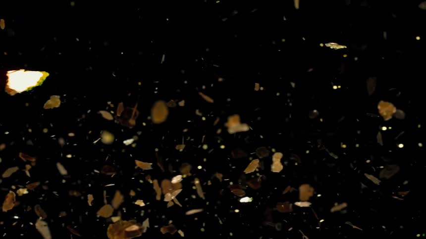 Abstract footage of confetti and golden flakes floating in the air and reflecting light