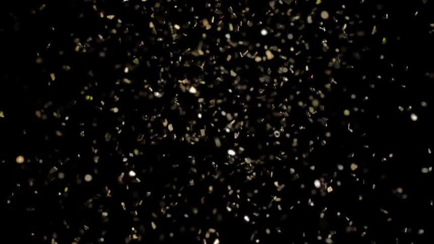 Confetti explosion showering down on black background and flying in the air