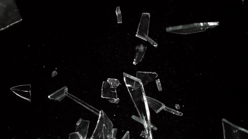Pieces of glass are thrown into the air against the dark background