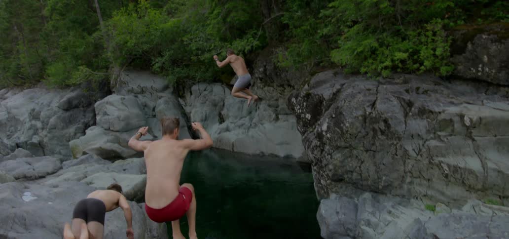 Three men jumping from tall rocks into water