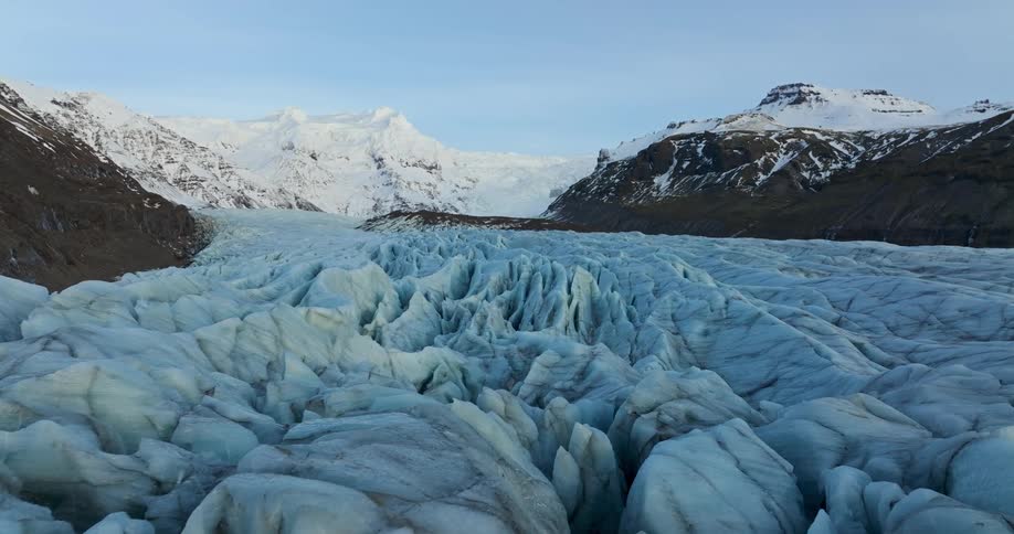 Rugged craggy glacier fills the valley between snowy mountains