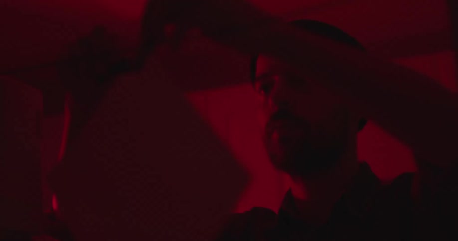 A man developing film in a dark room takes a photograph and clips to a line to dry