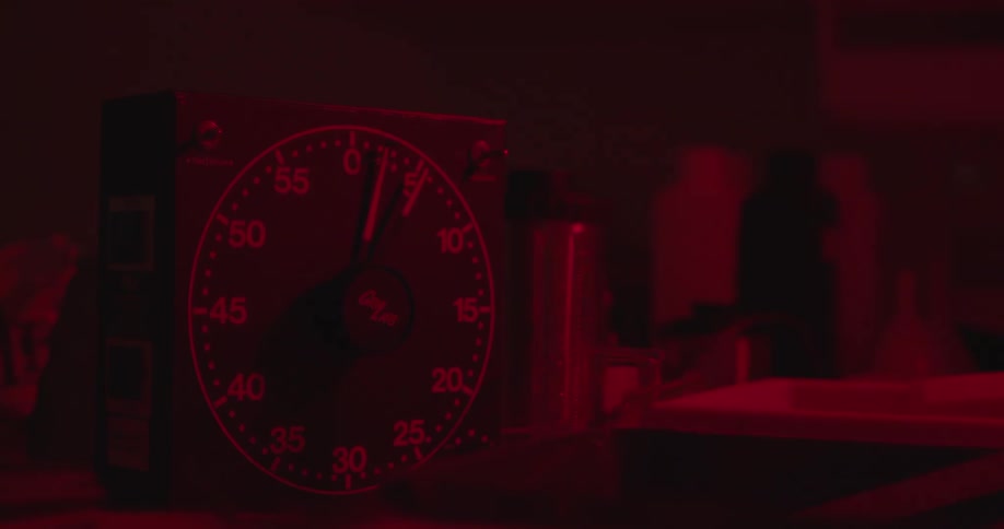Man sets and runs timer while developing film in a darkroom