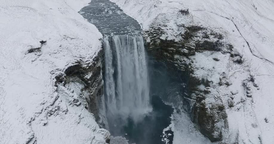 A large waterfall is in the center of the snow
