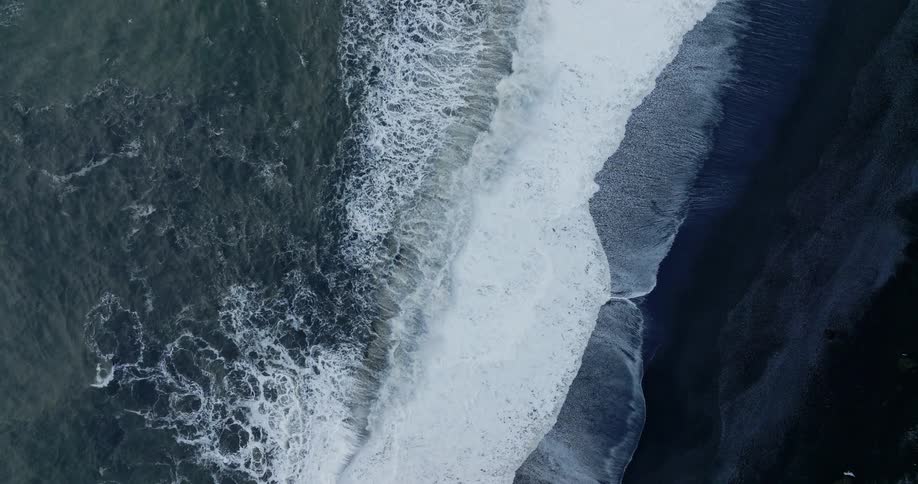 Seagulls flying above curling breaking waves on a cliff lined coast