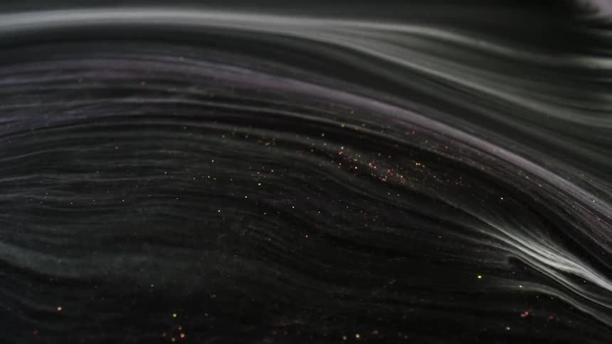 A thick black liquid with red glitter flowing to the left