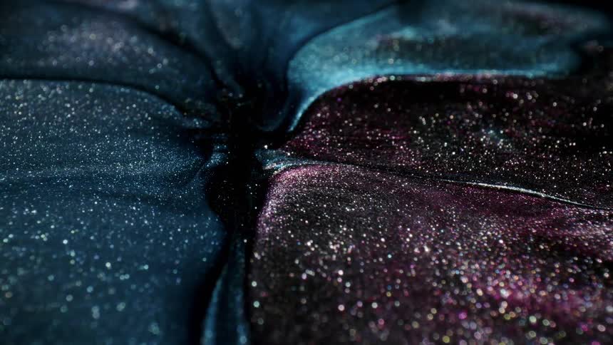 Glitter filled streams of paint merge and swirl