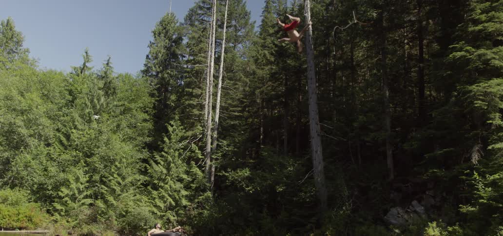 Man doing a flip from a rope swing into water