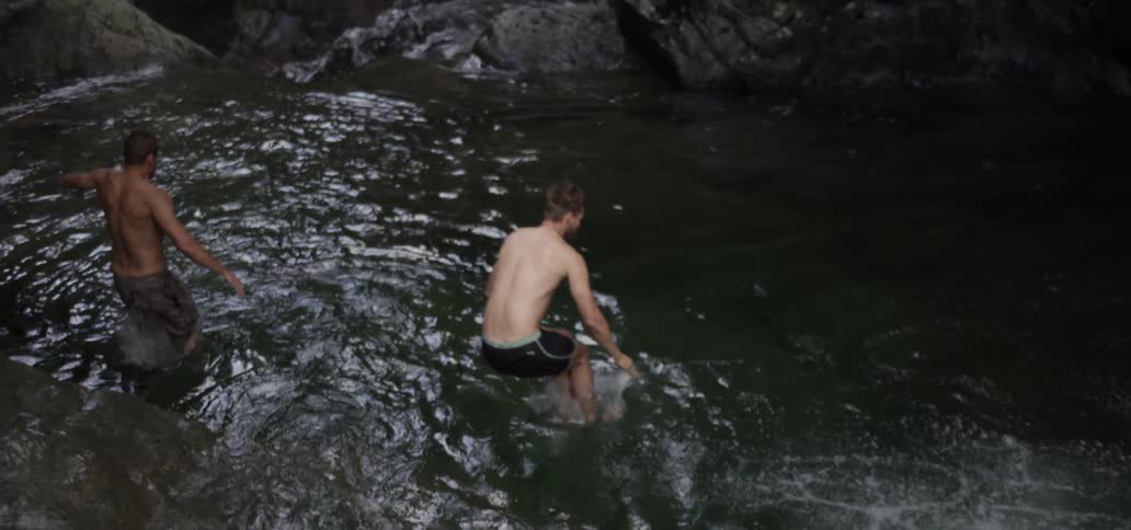 Men jumping off boulders and into a river