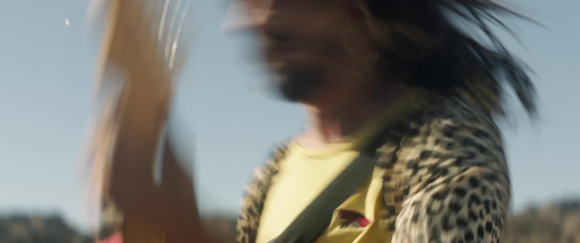 A guitarist head banging while performing outside
