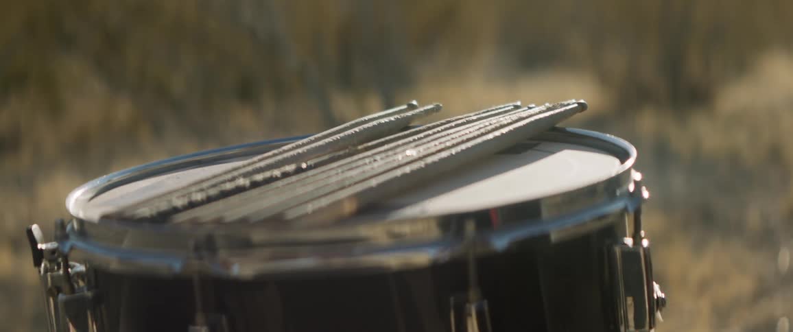 Drum sticks rest on top of a drum outdoors