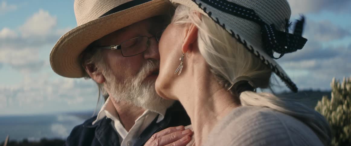 Older couple seeing ocean view on windy day kiss