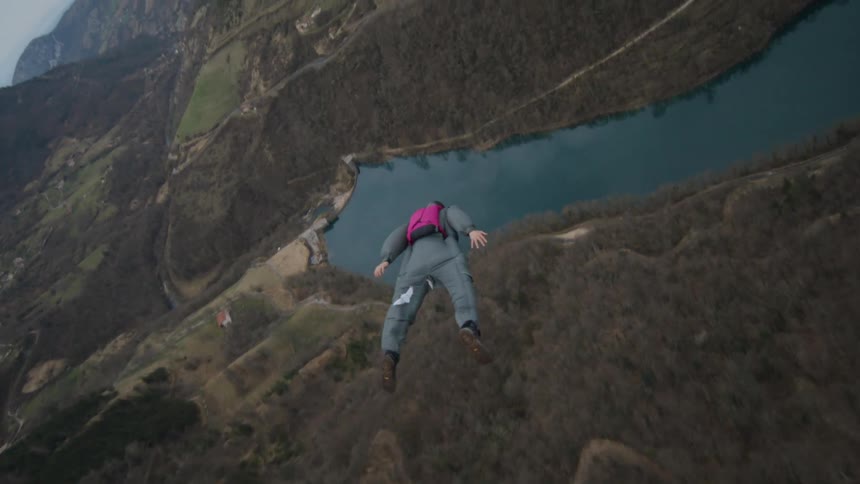A man jumps off a cliff and flies through a canyon before deploying his parachute