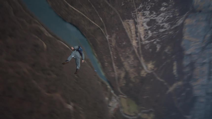 Person jumps off cliff and free falls before pulling chute