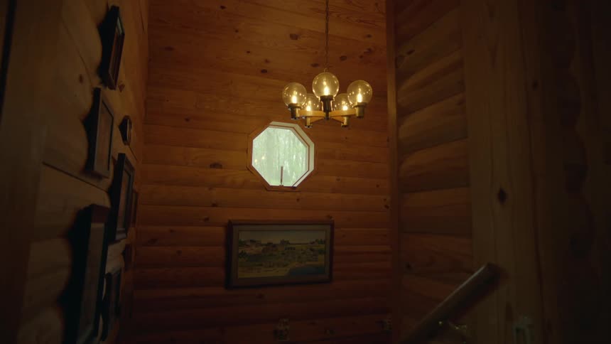 A painting hangs on a wall below a window in a home