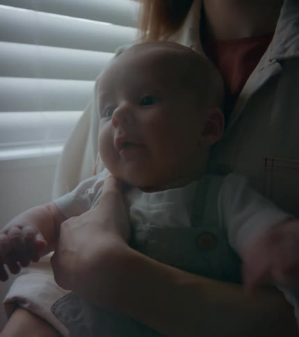 A woman holding her infant son in her lap wipes his face