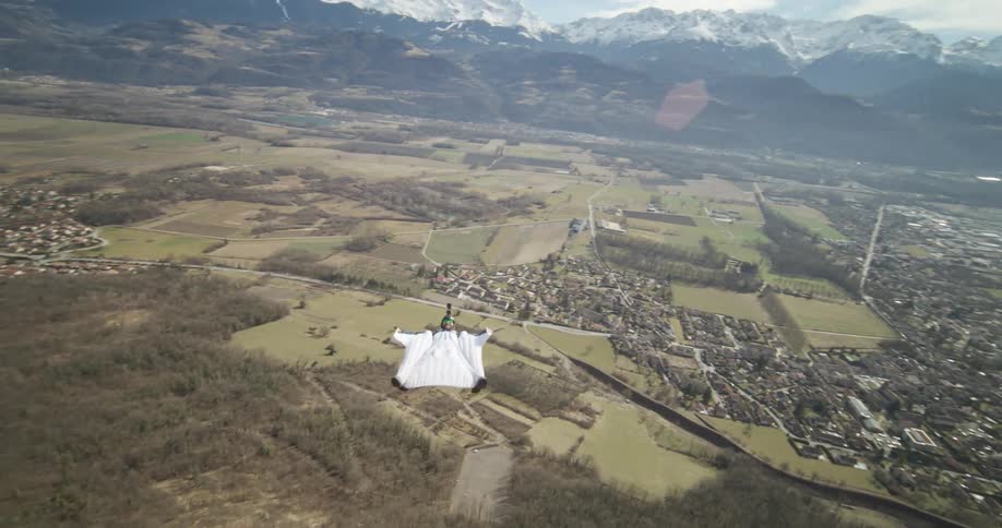 A person jumping from a mountainside in a wingsuit and soaring through the air