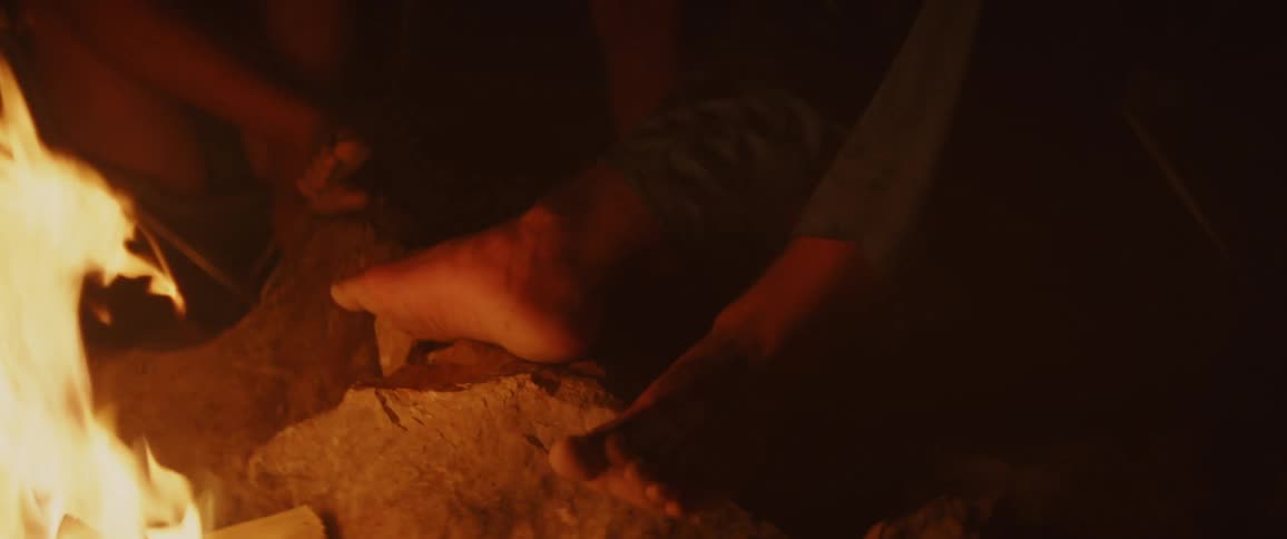 Two people warming their feet near a fire