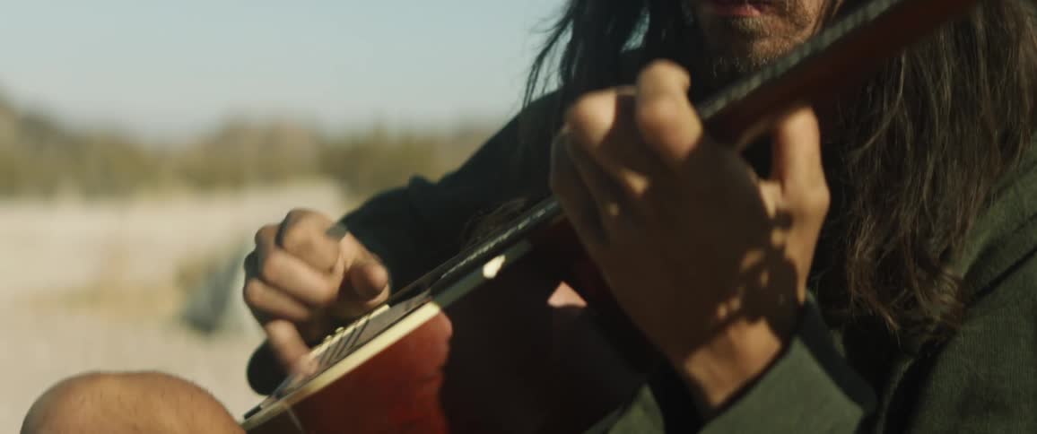 A man playing a stringed instrument in nature
