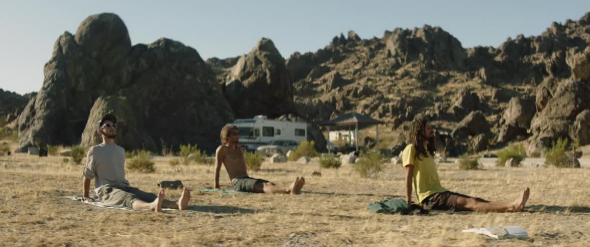 Three men doing yoga at a desert campsite