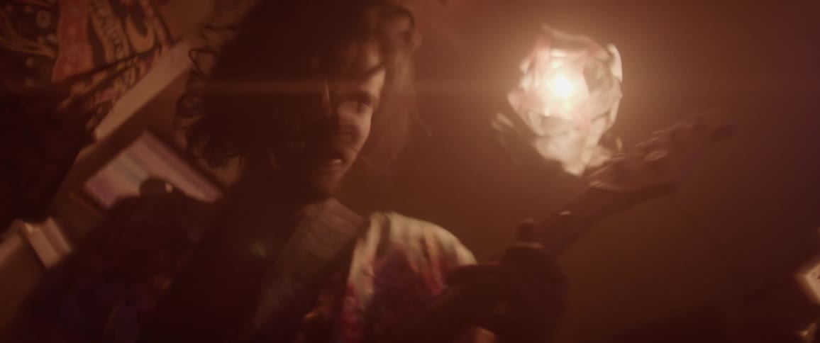 A man headbanging while playing a guitar beneath a light fixture