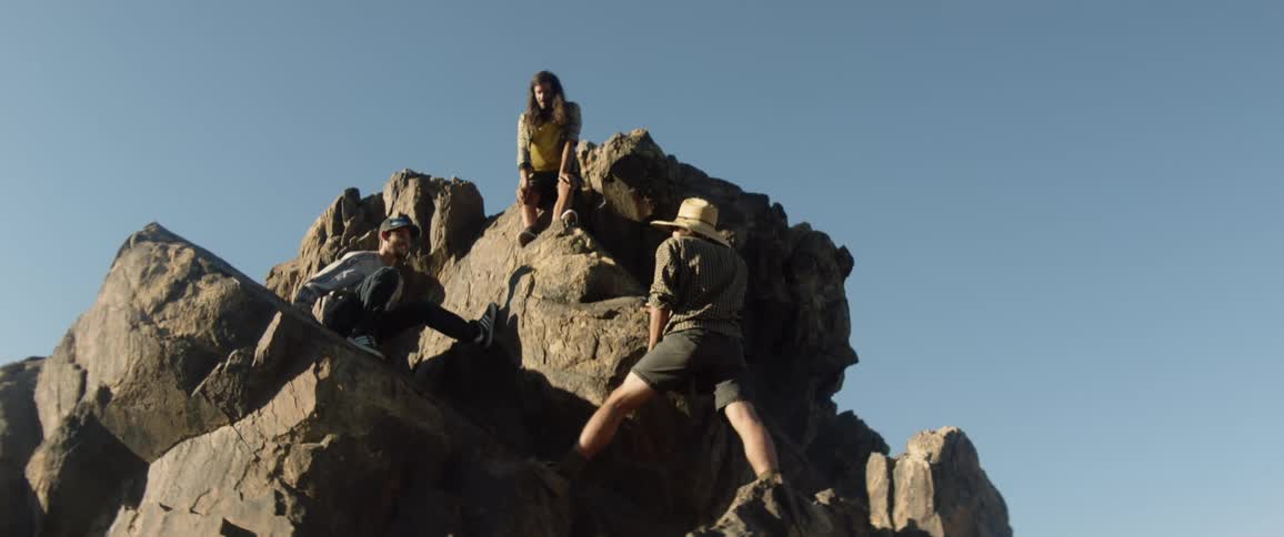 Three men rock climbing rest on a mountain