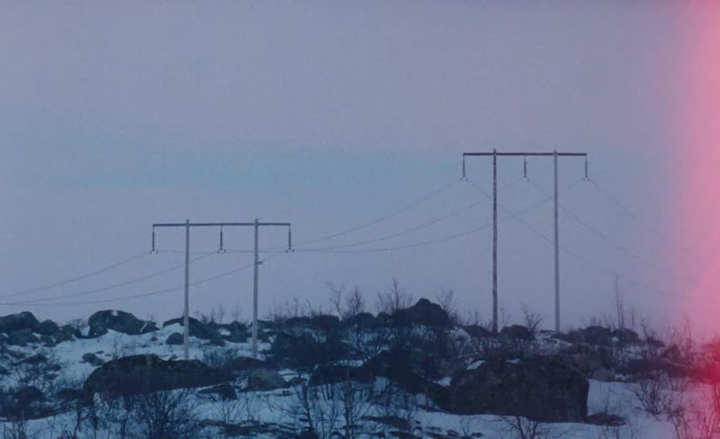 Utility poles in a snowy field with rocks