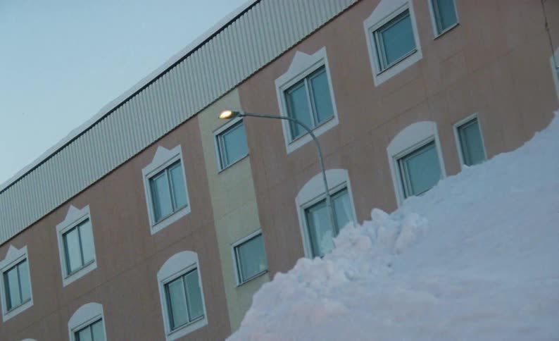 A snow bank outside a building complex with windows