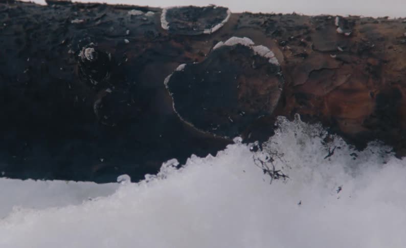 A smoldering tree trunk lies in the snow and ice