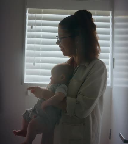 A woman talks to her infant son as she holds him at home