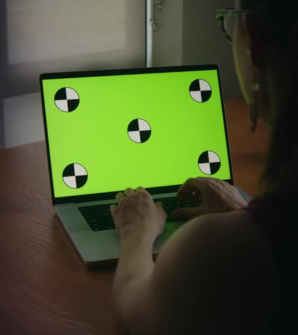 A woman types on a laptop at table indoors during the day