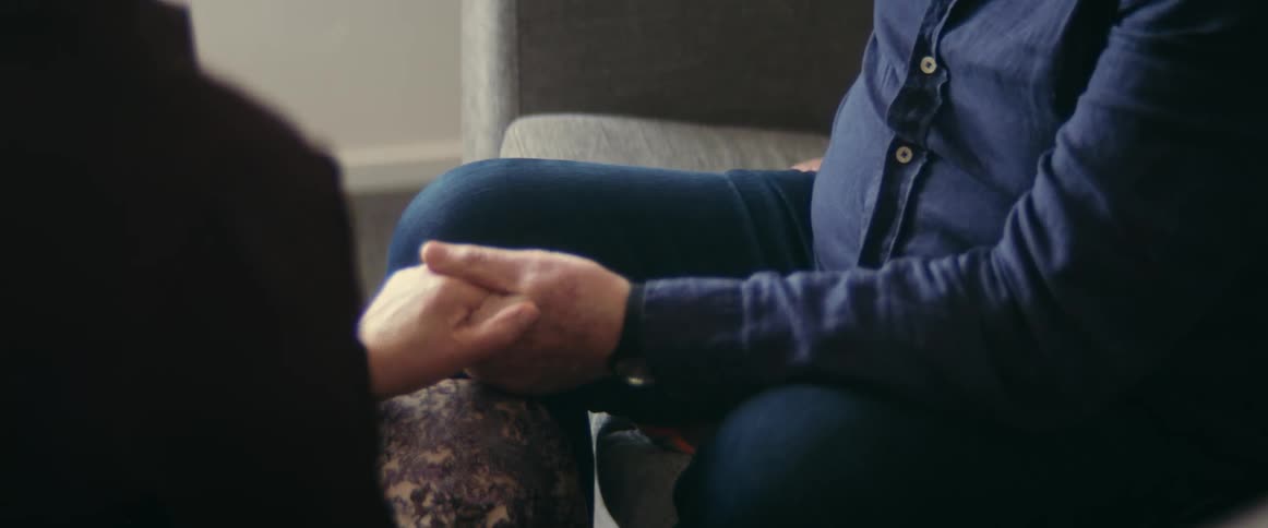 Elderly man wearing blue shirt and jeans gives woman a letter holding hands