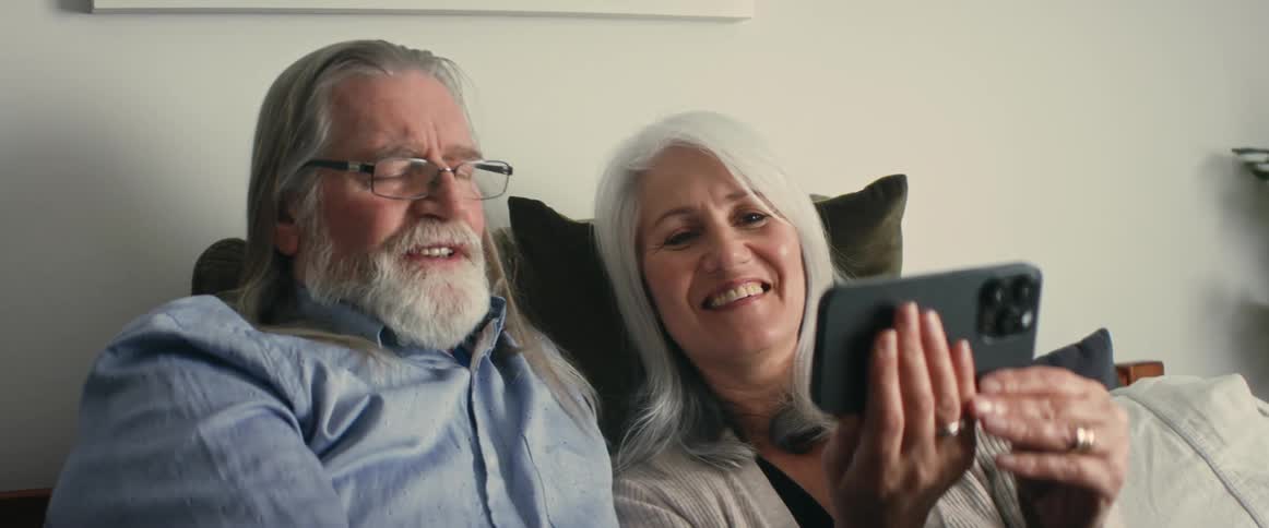 A man and woman looking at a cellphone smiling and looking at each other