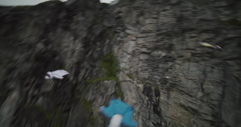 Four people para gliding jump off a cliff by a lake
