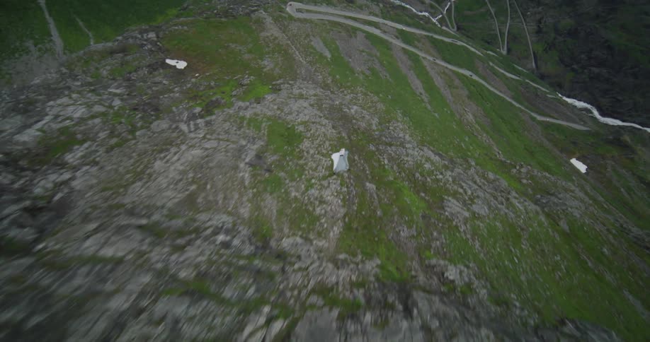 Man gliding down a green mountain passing a road