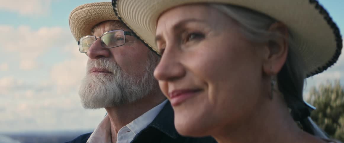 A man and a woman wearing hats are relaxing outside