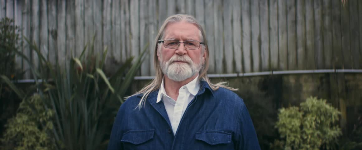A white man with glasses stares straight into the camera
