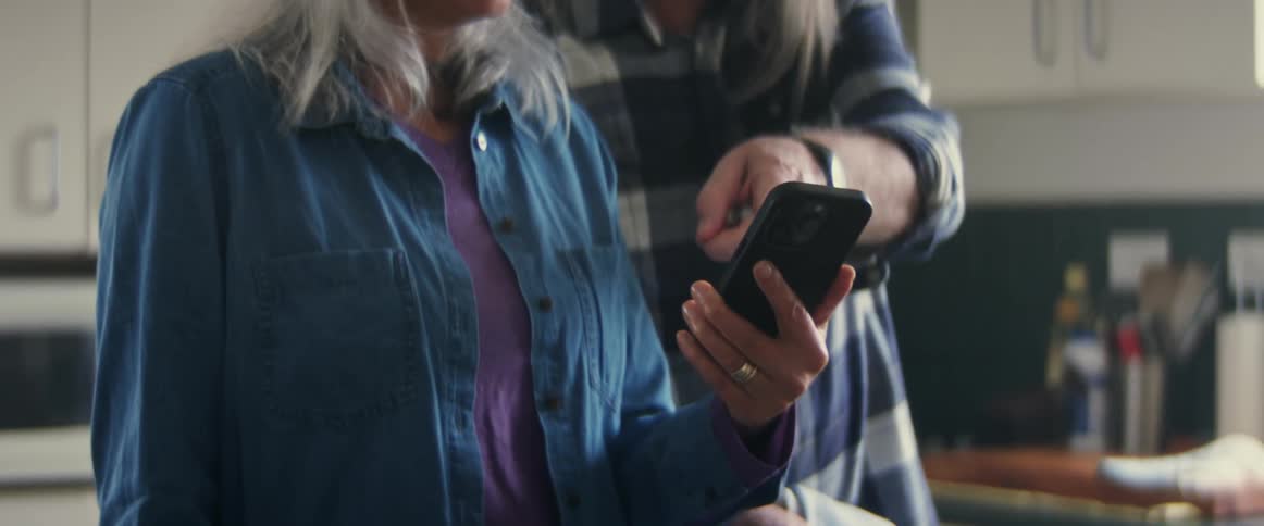 A elderly couple is looking at a phone inside of there home