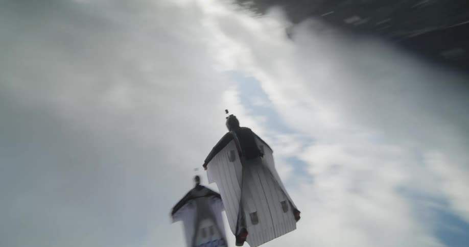 Wingsuit flyers over green fields and forests