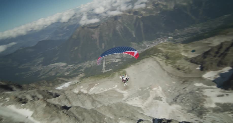 Man wearing parachute goes paragliding over snowy mountain