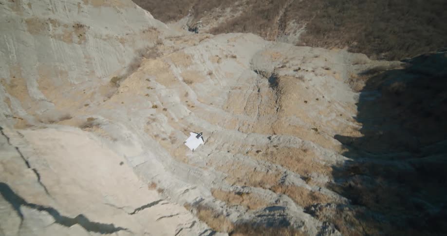 A man jumping off a cliff in a parachute suit