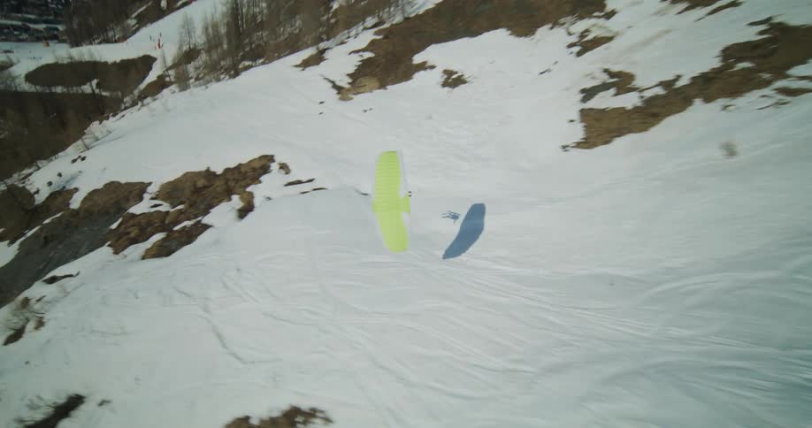 A person on skis paragliding through a snow covered valley