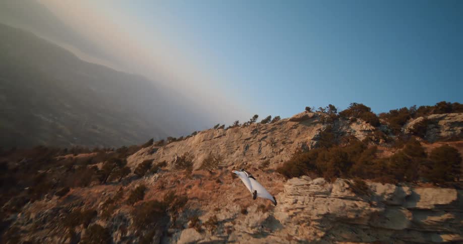 Man jumping off a cliff and doing a dive