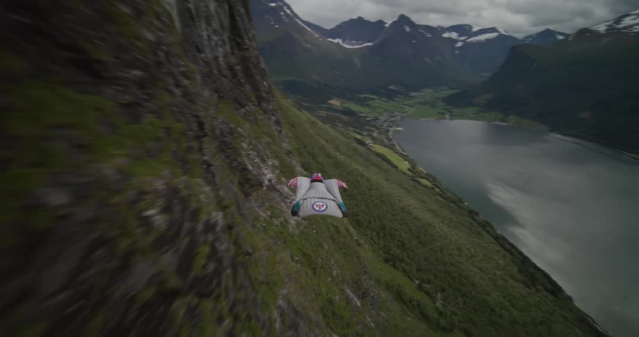 A person in a wingsuit gliding down over the side of a mountain